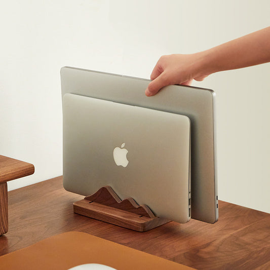 Walnut vertical laptop stand storing a laptop upright to free desk space